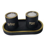 זוג פמוטים שחורים בעבודת יד עם כיתוב "שבת" ו"שלום" בצבע זהב, עשויים מבטון פולימרי, מונחים על מגש שחור עם מסגרת זהב.