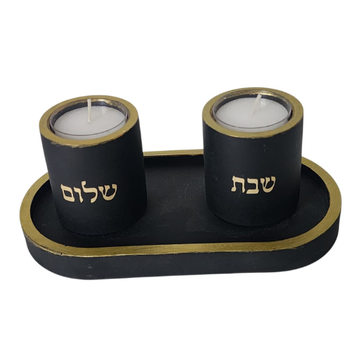 זוג פמוטים שחורים בעבודת יד עם כיתוב "שבת" ו"שלום" בצבע זהב, עשויים מבטון פולימרי, מונחים על מגש שחור עם מסגרת זהב.