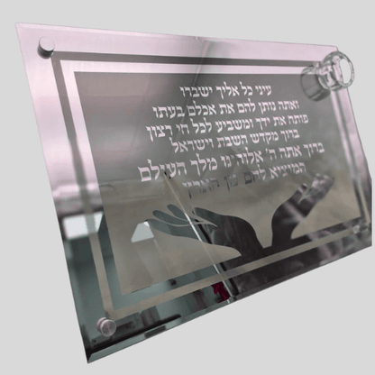 מגש חלה זכוכית עבה עם חריטה של ברכת "המוציא לחם מן הארץ" וקטע תהילים, עיטור זוג ידיים פתוחות ומוביל קטן למלח בפינה.

