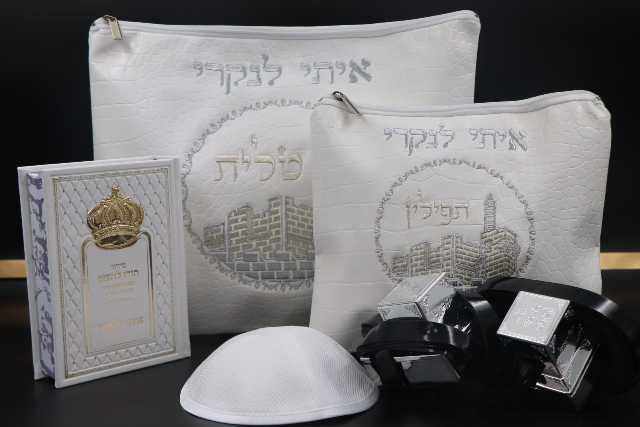 סט בר מצווה מהודר בצבע לבן הכולל תיק טלית גדול, תיק תפילין, כיפה לבנה, זוג תפילין שחורים וסידור עם כתר זהב על רקע שחור