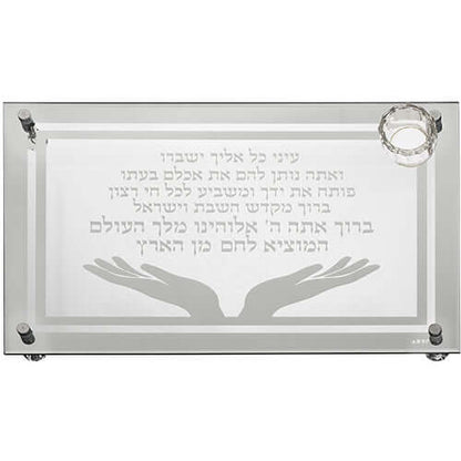 מגש חלה זכוכית עבה עם חריטה של ברכת "המוציא לחם מן הארץ" וקטע תהילים, עיטור זוג ידיים פתוחות ומוביל קטן למלח בפינה.

