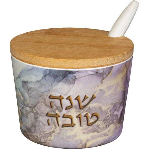 כלי עגול לדבש עשוי מלמין בגובה 6.5 ס"מ בדוגמת שיש בגווני סגול ואפור, עם כיתוב מוזהב "שנה טובה", מכסה עץ במבוק וכפית חרסינה לבנה. Translation missing: he.content.product_image_main