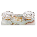 מגש זכוכית מלבני ומהודר להדלקת נרות שבת הכולל שני פמוטים שקופים דמויי פרח. המגש בעל עיצוב שיש עדין בגווני פסטל של ורוד, ירוק בהיר ונגיעות זהב, כשבמרכזו מופיע הכיתוב "שבת ויום טוב" באותיות זהב.